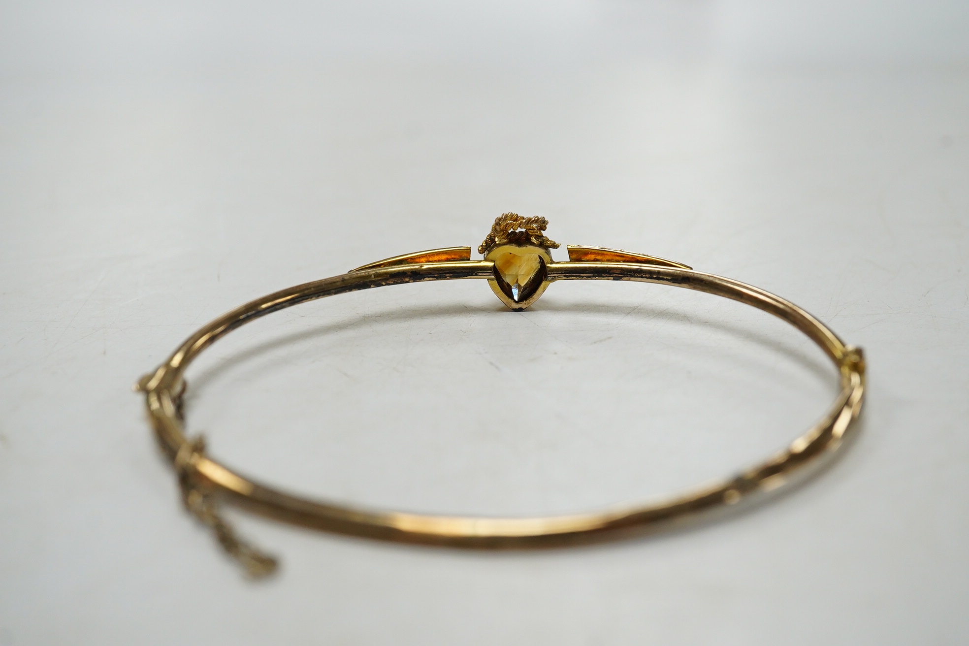 A Victorian yellow metal, citrine and seed pearl set hinged bangle, with heart shaped citrine, interior diameter 62mm, gross weight 4.6 grams, with fitted leather box. Condition - poor